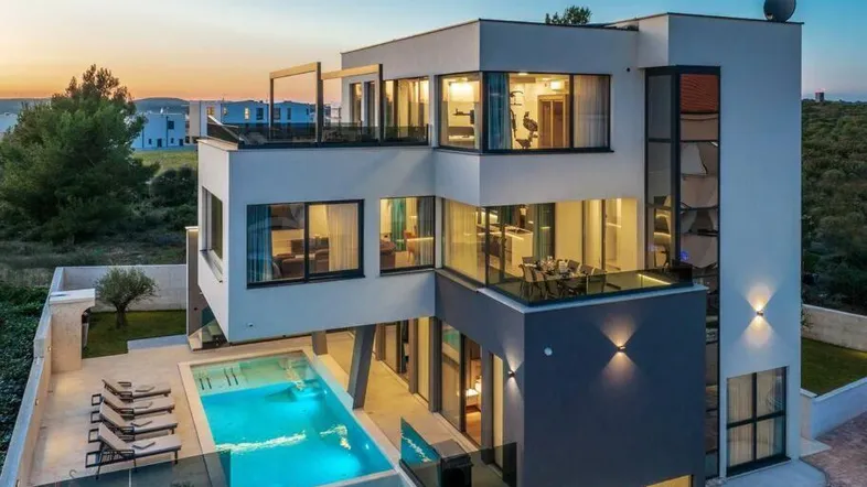 Moderne Villa bei Sonnenuntergang mit Infinity-Pool und großzügigen Terrassenbereichen.