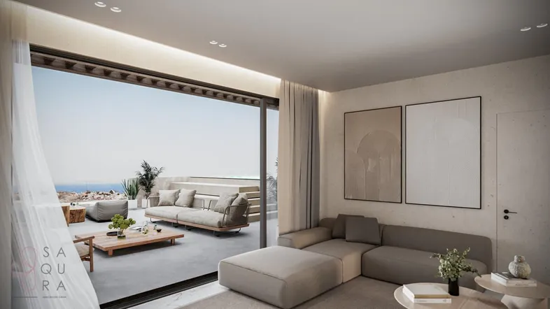 Modernes Wohnzimmer mit beigem Sofa, großen Schiebetüren und Meerblick von der angrenzenden Terrasse.