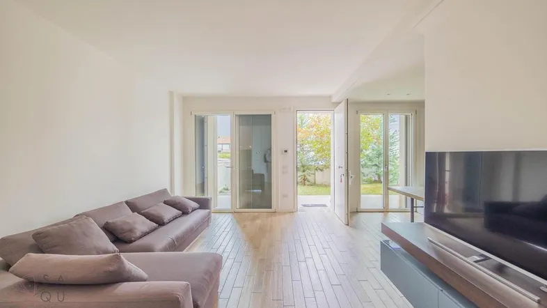 Helles Wohnzimmer mit großem Sofa, TV-Möbel und direktem Zugang zum Garten.