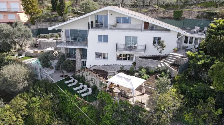 Großzügiges Anwesen mit moderner Architektur, mehreren Balkonen und Terrassen sowie einem Poolbereich.