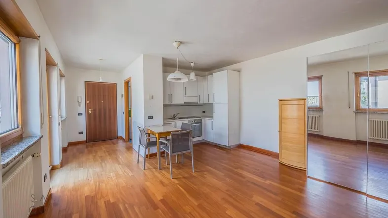 Helles Wohnzimmer mit offener Küchenzeile, Esstisch und Parkettboden.