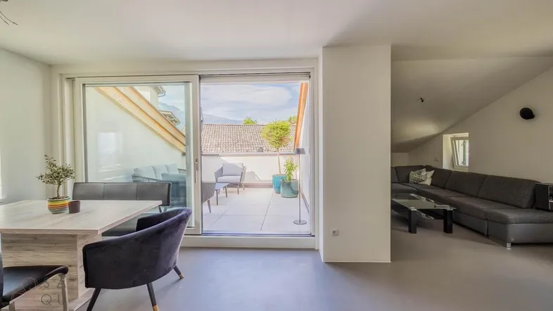 Heller offener Wohn- und Essbereich mit Zugang zu einer großzügigen Dachterrasse und moderner Einrichtung.