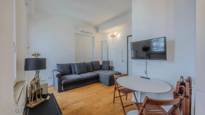 Helles Wohnzimmer mit modernem Sofa, Esstisch und Holzboden in offener Gestaltung.