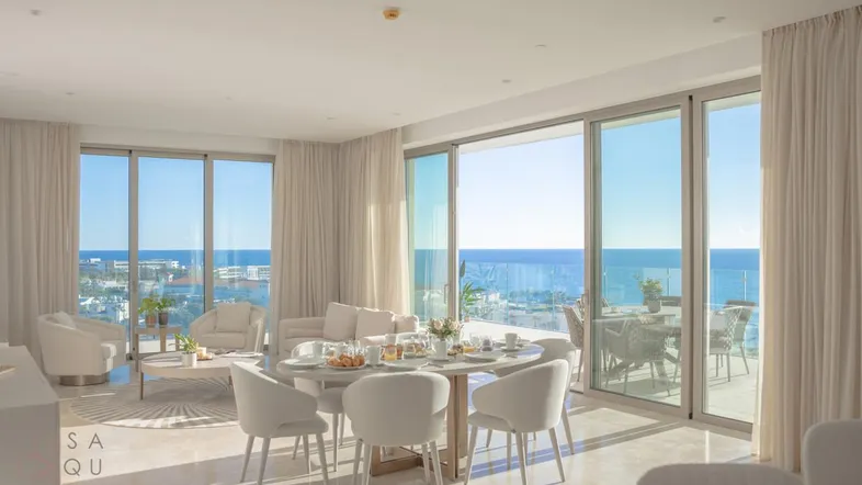 Helles, modernes Wohn- und Esszimmer mit großen Fenstern und atemberaubendem Meerblick sowie Zugang zum Balkon.