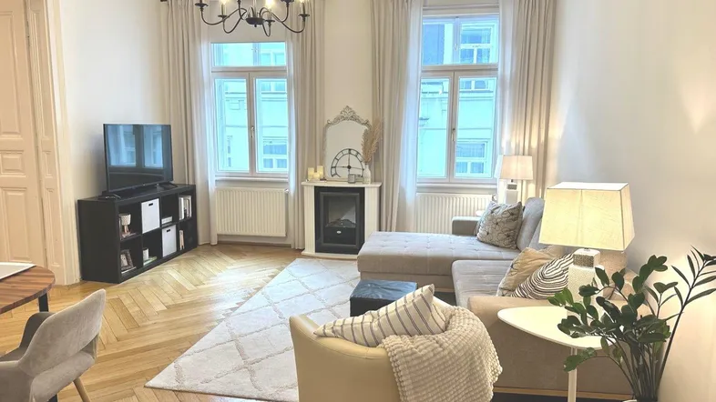Helles Wohnzimmer mit Fischgrätparkett, modernem Sofa und dekorativem Kamin.