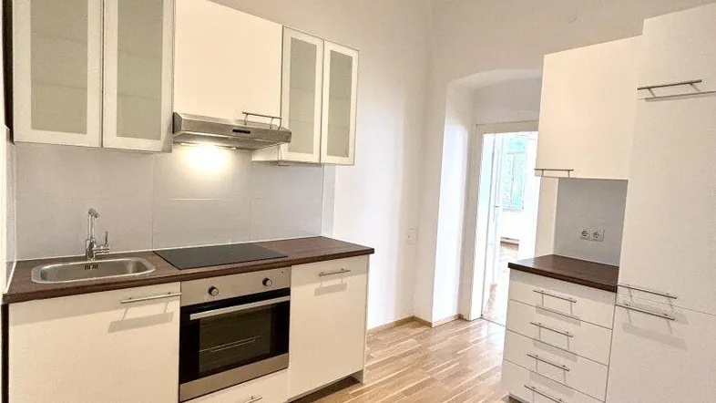 Moderne Einbauküche mit weißen Schränken, Holz-Arbeitsplatten und integrierten Geräten.