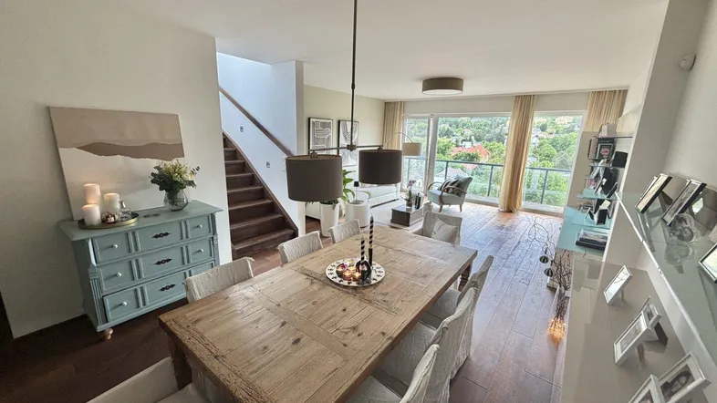 Heller Wohn- und Essbereich mit Holzboden, großem Esstisch und Zugang zu einem Balkon mit Weitblick.