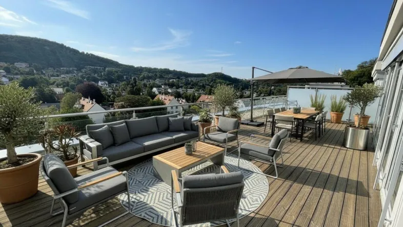 Geräumige Dachterrasse mit bequemen Outdoor-Möbeln, Pflanzen und weitem Blick über die grüne Landschaft.