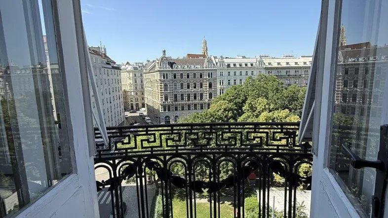 Blick vom Balkon auf eine grüne Parkanlage und die umliegende historische Stadtarchitektur.