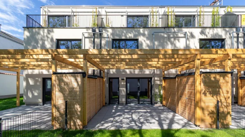 Moderne Reihenhäuser mit privaten Terrassen, Holzpergolen und Zugang zum Gartenbereich.