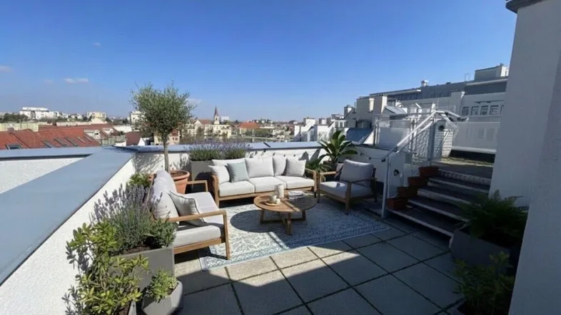 Geräumige Dachterrasse mit modernen Gartenmöbeln, Pflanzen und weitem Blick über die Stadt.