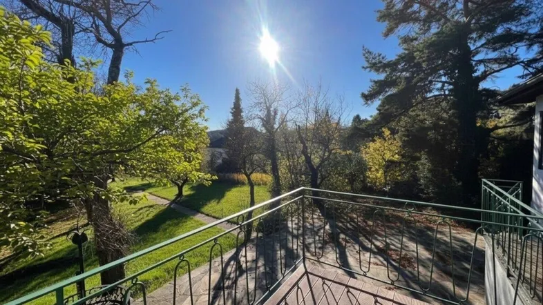 Sonniger Balkon mit Holzboden und schmiedeeisernem Geländer, bietet einen weiten Blick ins Grüne.