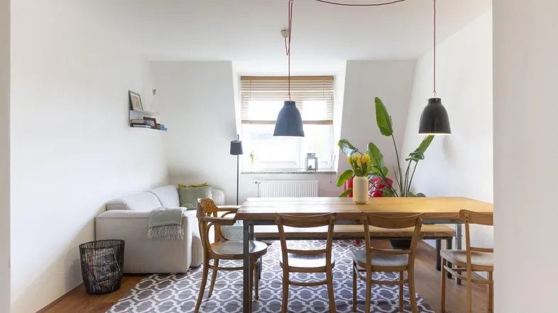 Helles Wohn- und Esszimmer mit Holzboden, modernem Teppich und stilvollen Pendelleuchten.