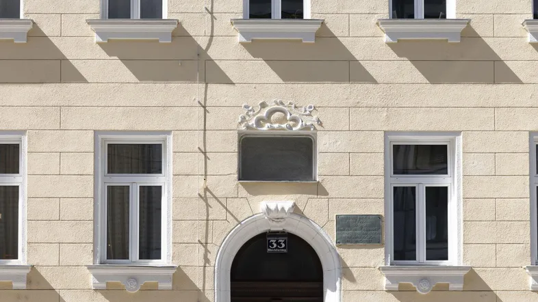Detailansicht der historischen Fassade mit Eingangstür und Fensterornamenten.