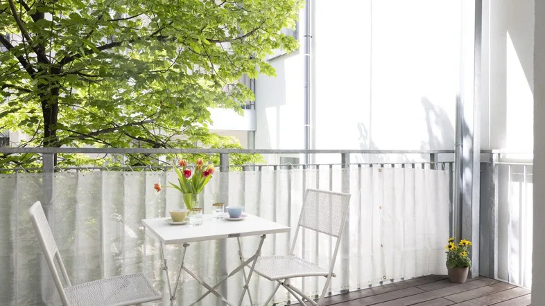 Gemütlicher Balkon mit Holzboden, Sitzgelegenheiten und Blick ins Grüne.