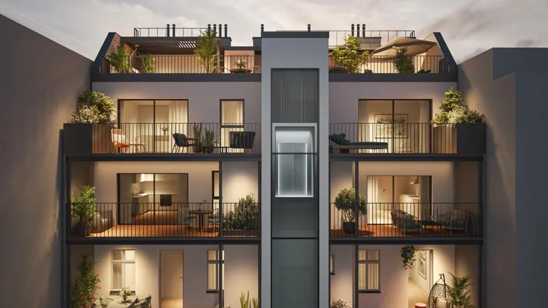 Moderne Fassade eines Wohngebäudes mit mehreren Balkonen und einem externen Aufzug.