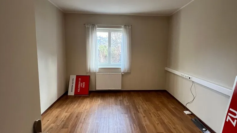 Helles und gepflegtes Büro mit Laminatboden, einem Fenster und natürlichem Lichteinfall.
