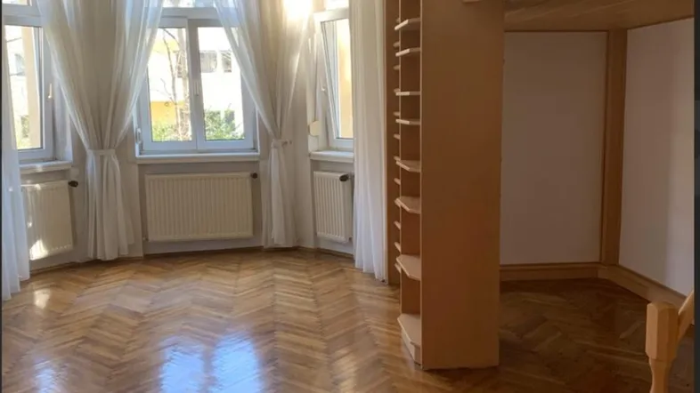 Helles Schlafzimmer mit Fischgrätparkett, großen Fenstern und einem Hochbett mit integriertem Regal.