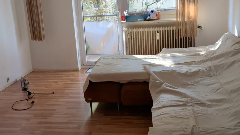 Helles Schlafzimmer mit Parkettboden, Balkonzugang und einem modernen Deckenleuchter.