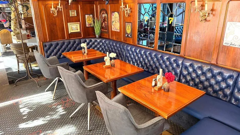 Gemütlicher Restaurantbereich mit blauen Lederbänken, Holztischen und Wandvertäfelung in klassischem Stil.