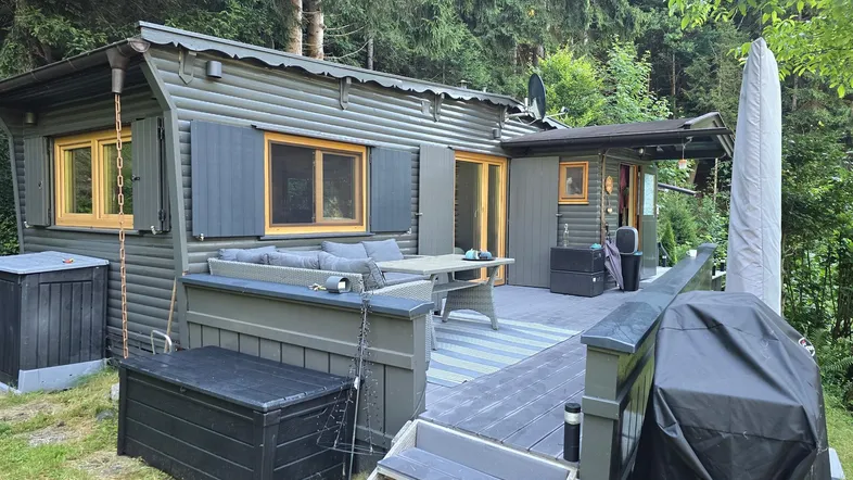 Gemütliche Terrasse mit Sitzgelegenheiten und Grillbereich, umgeben von grünen Bäumen.