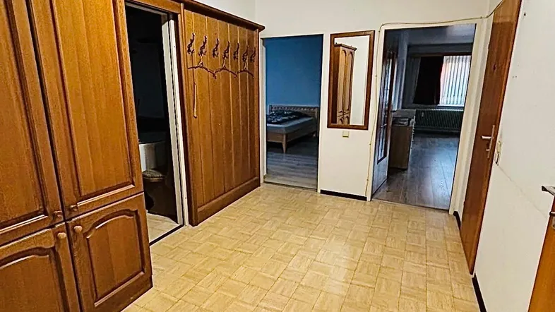 Geräumiger Flur mit Holzschränken und hellem Vinylboden, der zu verschiedenen Zimmern führt.