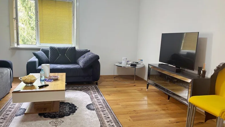 Helles Wohnzimmer mit Holzboden, bequemen Sofas und einem Fernseher für entspannte Abende.