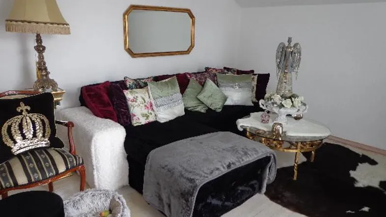 Gemütliches Wohnzimmer mit Plüschsofa, elegantem Spiegel und Kronleuchter, dekoriert im opulenten Stil.