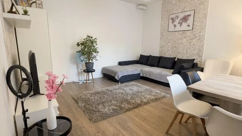 Heller Wohn- und Essbereich mit modernem Sofa, Esstisch und Holzboden.