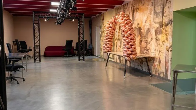 Großer offener Raum mit Betonboden, roter Decke und professioneller Beleuchtung, ideal für Veranstaltungen oder Büronutzung.