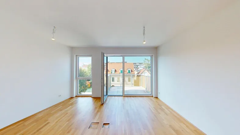 Helles Wohnzimmer mit Parkettboden, weißen Wänden und Zugang zu einem Balkon mit Stadtblick.