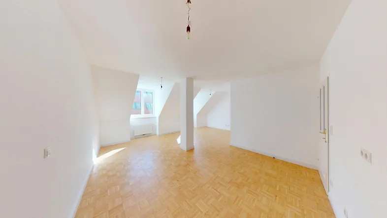 Helles, geräumiges Zimmer mit Parkettboden und Dachschrägen, ideal als Wohnbereich nutzbar.