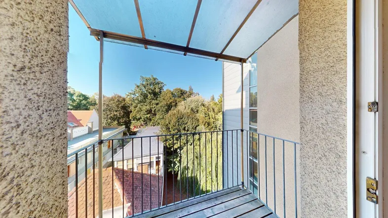 Überdachter Balkon mit Holzboden und Blick ins Grüne, ideal für entspannte Stunden im Freien.