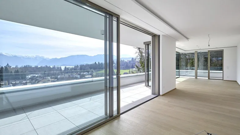Helles, modernes Wohnzimmer mit großen Schiebetüren zur Terrasse und weitem Blick auf die Berge.