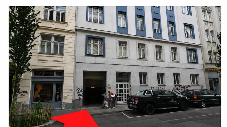Gebäudefassade mit Einfahrt zur Schottenfeldgasse und parkenden Autos.