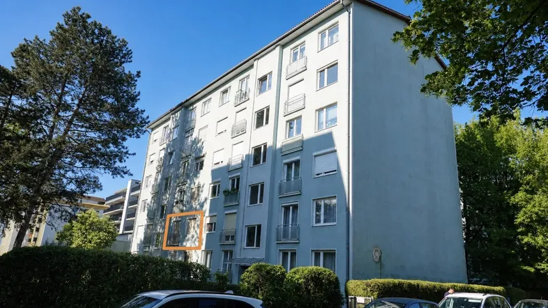Mehrfamilienhaus mit hellblauer Fassade und mehreren Balkonen an einem sonnigen Tag.