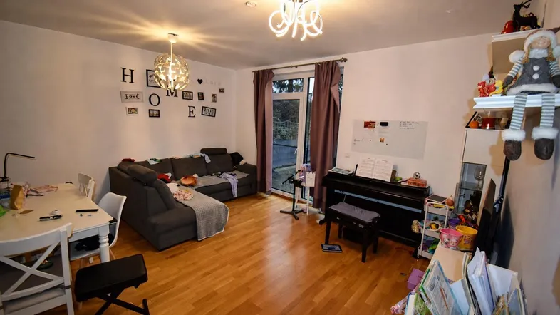 Helles Wohn-Esszimmer mit Holzboden, gemütlichem Sofa, Esstisch und Zugang zu einem Außenbereich.