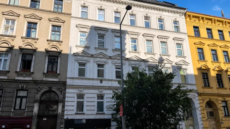 Historisches Mehrfamilienhaus in städtischer Umgebung mit klassischer Fassade und Dachausbau.