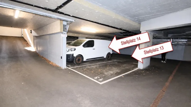 Tiefgarage mit markierten Stellplätzen und einem Lieferwagen, beleuchtet von Deckenlampen.