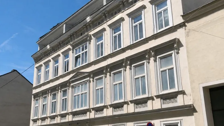 Historisches Gebäude mit klassischer Fassade und vielen Fenstern unter blauem Himmel.