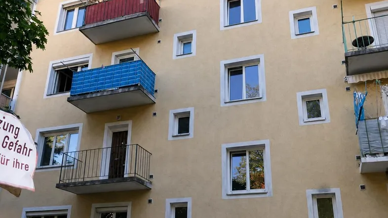 Mehrstöckiges Wohngebäude mit mehreren Balkonen und gelber Fassade unter blauem Himmel.