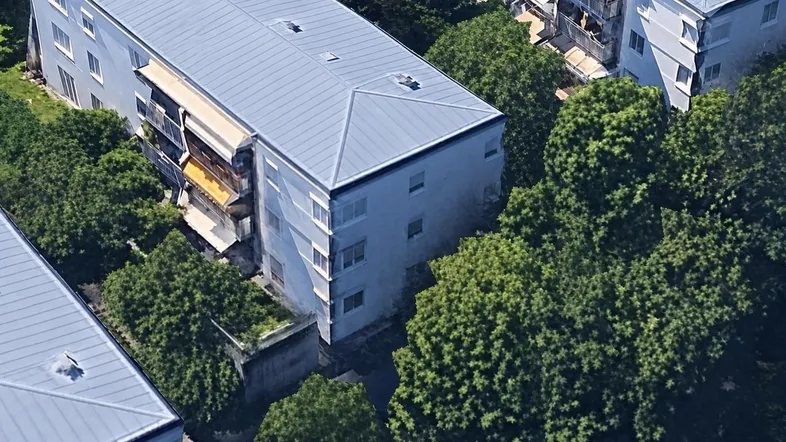 Luftaufnahme von Wohngebäuden mit Balkonen, umgeben von dichtem Grün und Bäumen.