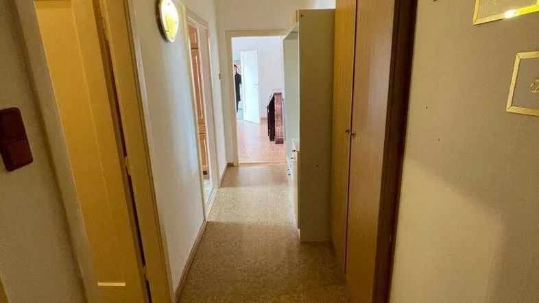 Langer Flur mit Korkboden und Holzdeckenpaneelen, der zu weiteren Räumen führt.
