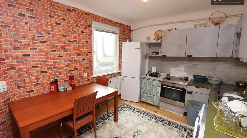 Küche mit Esstisch, Kühlschrank und Herd, Backstein-Tapete und Teppichboden.