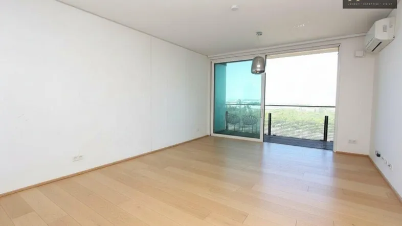 Helles Wohnzimmer mit Holzboden, Klimaanlage und Zugang zu einem Balkon mit Weitblick.