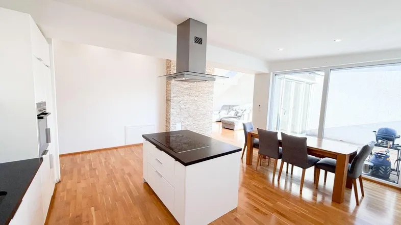Heller offener Wohn- und Essbereich mit moderner Küche, Kochinsel und Zugang zur Terrasse.