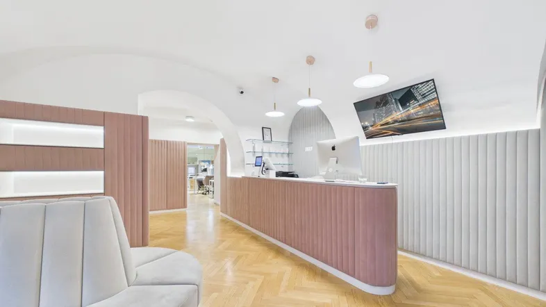 Moderner Empfangsbereich mit rosafarbenem Tresen, Fischgrätparkett und gewölbter Decke, ideal für ein Geschäft.