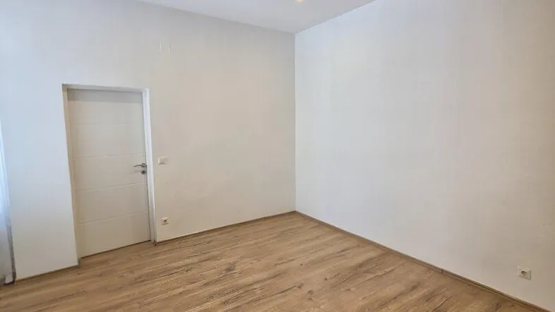 Helles, leeres Zimmer mit modernem Laminatboden und Deckenstrahlern, bereit zur individuellen Gestaltung.