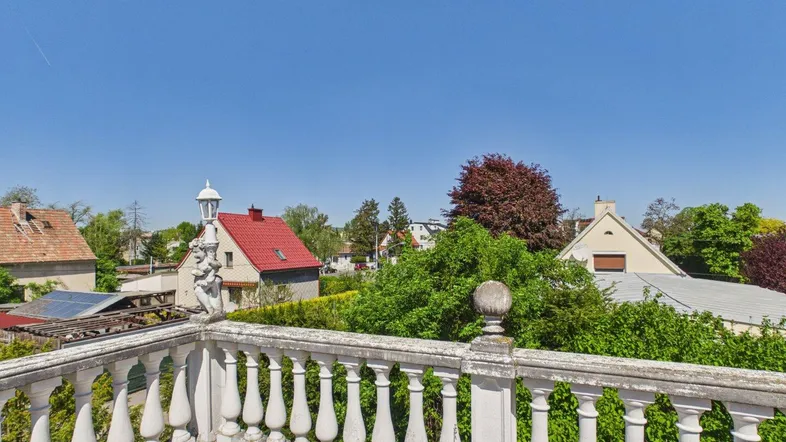 Sonnenterrasse mit Balustrade und Blick auf die umliegenden Häuser und Gärten.