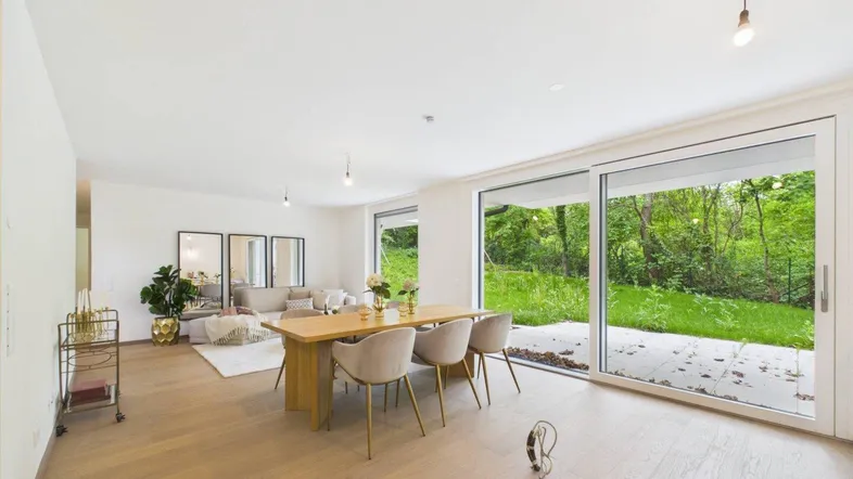 Heller, offener Wohn- und Essbereich mit Holzboden und Zugang zur Terrasse mit Gartenblick.